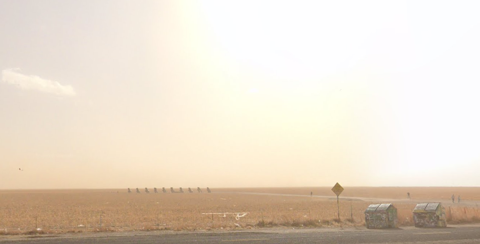 Image of Cadillac Ranch from a distance with the sun coming up behind the cars.