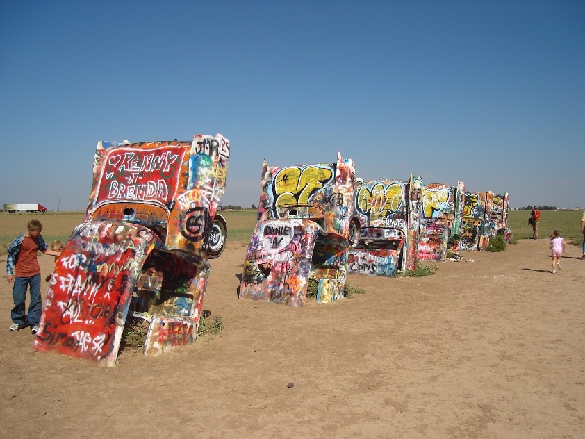 Landscape shot of spray-painted Cadillacs against a blue sky.