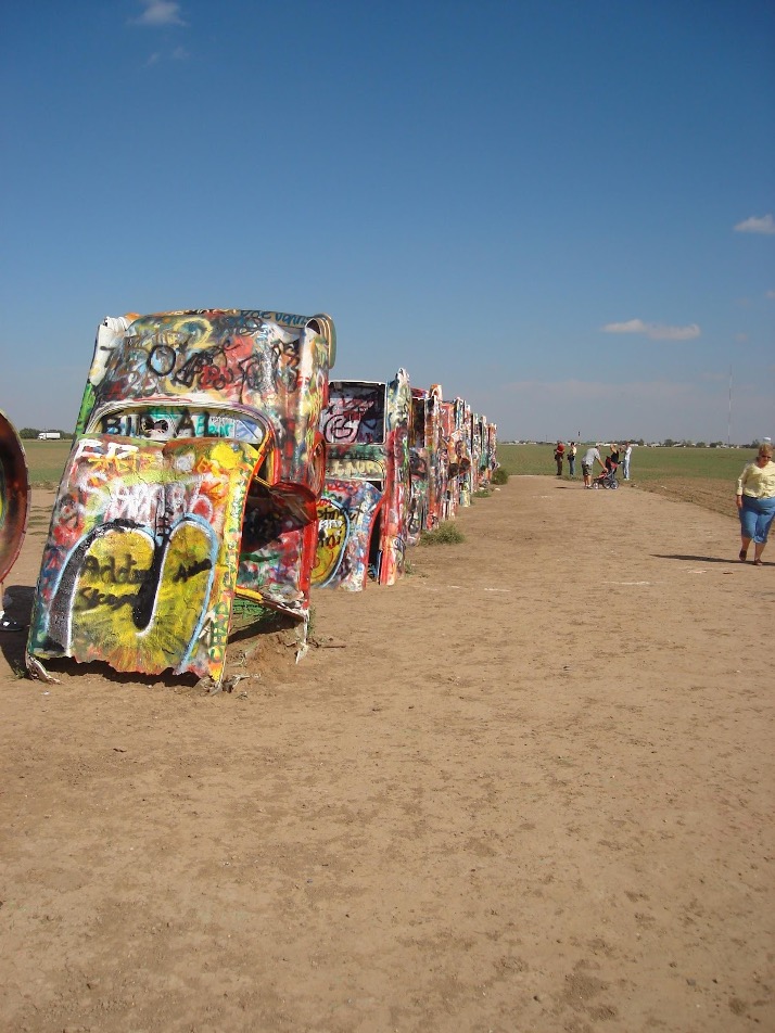 Several spray-painted Cadillacs are featured in a row.